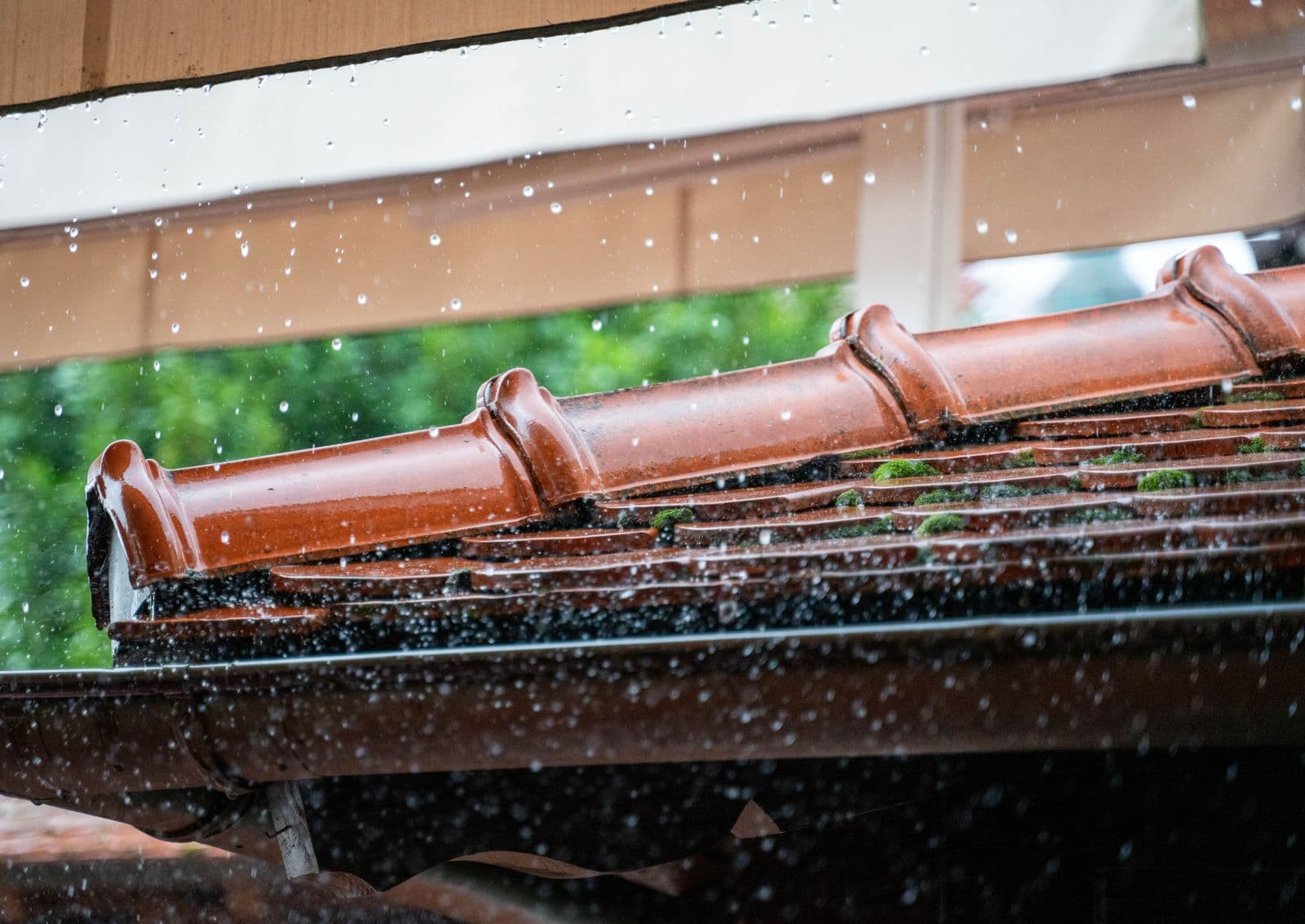 Rain running over terracotta roof tiles.